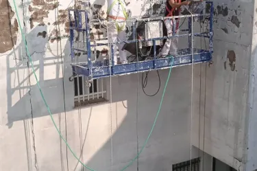 Trabajadores realizando rehabilitación y pintura en patio interior de edificio en Sevilla, con sistemas de seguridad vertical
